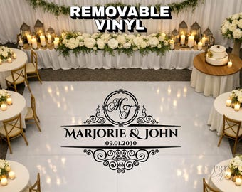 May include: A white removable vinyl dance floor decal featuring a black ornate monogram with the initials MJ, the names MARJORIE & JOHN, and the date 09.01.2030, centered within a decorative scrollwork frame on a glossy white floor surface.