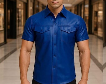 Può includere: Una camicia di pelle blu cobalto a maniche corte, con due tasche sul petto e chiusura con bottoni. La camicia è abbinata a pantaloni neri. Il colore della camicia è vibrante e il materiale appare liscio.