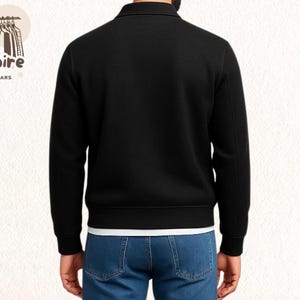 Pode incluir: Casaco preto com z&iacute;per e gola. Usado sobre uma camiseta branca e jeans azuis. O logotipo "Empire Outwears" &eacute; vis&iacute;vel no canto superior esquerdo.