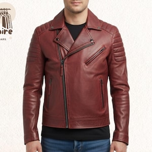 Könnte beinhalten: Burgunderfarbene Lederjacke mit asymmetrischem Reißverschluss, Reverskragen und gesteppten Schulterdetails. Die Jacke hat mehrere Reißverschlusstaschen und eine taillierte Passform. Das Logo "Empire Outwears" ist oben links sichtbar.