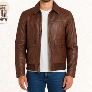 May include: A brown leather jacket featuring a collared neckline, two front pockets, and a ribbed hem. The jacket has a zip closure and is worn over a white t-shirt and blue jeans. The "Empire Outwears" logo is visible in the upper left corner.