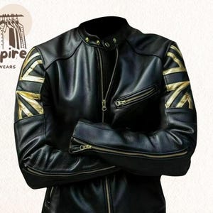 Può includere: Giacca in pelle nera con design a bandiera Union Jack dorata sulle spalle. La giacca ha una chiusura con zip, più tasche con zip e un colletto rialzato. Il logo "Empire Outwears" si trova nell'angolo in alto a sinistra.