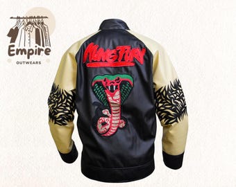 May include: Black satin jacket with cream-colored sleeves and a black collar. The back features a large embroidered cobra design and the word "NINETEEN" in red. The sleeves have a black decorative pattern.