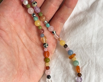 Peut inclure: Un collier de perles composé d'une variété de pierres précieuses multicolores, de perles et de perles en jaspe dalmatien tacheté. Le brin présente des formes rondes, facettées et irrégulières dans des tons de rose, bleu, vert, jaune, orange et blanc.