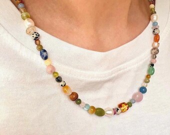 Peut inclure: Un collier de perles colorées avec une variété de formes et de tailles. Le collier présente un mélange de couleurs, dont le rose, le bleu, le vert et l'orange. Les perles sont enfilées sur un cordon délicat.