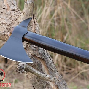 Pode incluir: Machado com cabe&ccedil;a preta e cabo de madeira escura. A cabe&ccedil;a do machado tem uma l&acirc;mina curva e uma ponta no lado oposto. O cabo &eacute; liso e polido. O logotipo Axe Master est&aacute; no canto inferior esquerdo.