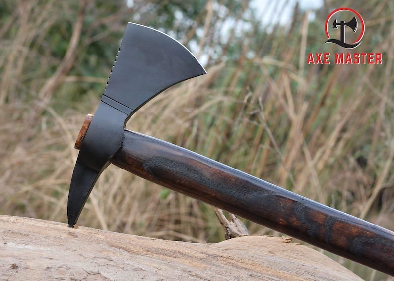 Pode incluir: Machado com uma cabe&ccedil;a preta fosca escura e um cabo de madeira. A cabe&ccedil;a do machado tem uma l&acirc;mina curva e uma ponta no lado oposto. O cabo &eacute; marrom escuro com gr&atilde;o de madeira vis&iacute;vel. O texto "AXE MASTER" &eacute; vis&iacute;vel.