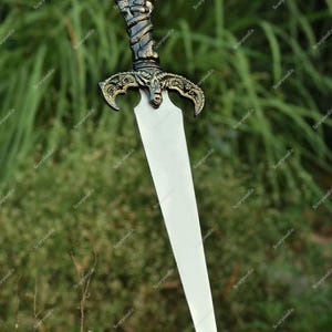 May include: A decorative dagger with a silver blade and an ornate handle. The handle features a skull design at the top and a twisted, serpent-like pattern. The hilt has an intricate, gold-colored design.