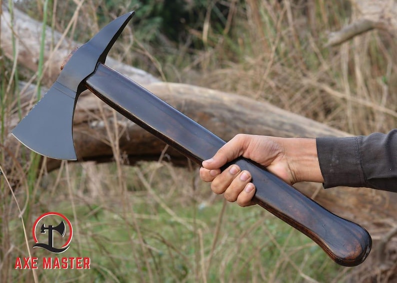 Pode incluir: Machado com uma l&acirc;mina cinza escuro e um cabo de madeira escura. A cabe&ccedil;a do machado tem um topo curvo e uma borda dentada. A al&ccedil;a &eacute; segurada em uma m&atilde;o. O logotipo Axe Master est&aacute; no canto inferior esquerdo.