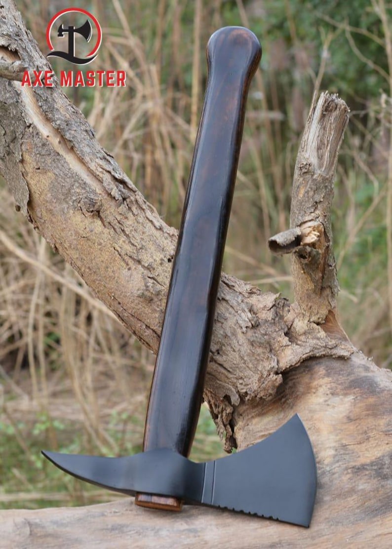 Pode incluir: Machado com cabo de madeira escura e cabe&ccedil;a preta. A cabe&ccedil;a do machado tem uma l&acirc;mina afiada e uma borda serrilhada. O cabo &eacute; longo e curvo, com o texto "AXE MASTER" em vermelho.