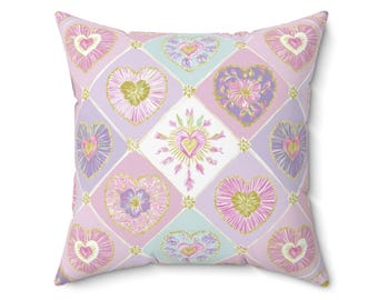Cojín decorativo con forma de corazón en tonos pastel, con detalles en rosa y lavanda, ideal para el salón o el dormitorio.