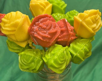 Può includere: Un bouquet di rose commestibili dai colori vivaci: giallo, rosso e verde. I fiori sono presentati in un barattolo di vetro trasparente, su sfondo verde. Una dolcezza.