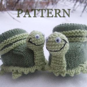 Könnte beinhalten: Ein Paar grüne gestrickte Babyschuhe in Form von Schildkröten. Die Schuhe haben einen grün-weiß gestreiften Bund und einen gehäkelten Schildkrötenkopf mit schwarzen Augen und einem Lächeln.