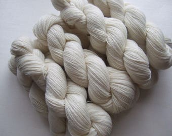 May include: Close-up of off-white yarn skeins, tightly twisted and arranged in a cluster. The yarn appears soft and textured, ideal for knitting or crocheting projects. The neutral color suggests versatility for various craft projects.