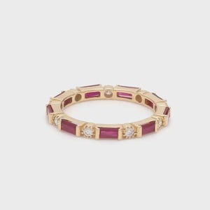 Peut inclure: Une bague en or ornée d'alternances de pierres précieuses rubis rectangulaires et de petits diamants ronds. La bague présente un design continu, avec les pierres précieuses et les diamants sertis tout autour du bracelet. La bague est présentée sur fond blanc.