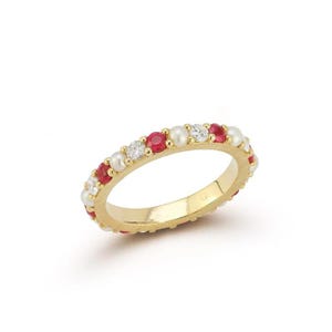 May include: A gold ring with alternating red gemstones, white pearls, and clear crystals. The ring has a polished gold band. The jewellery is set against a white background. A classic design.