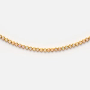 May include: A gold chain necklace featuring a continuous row of small, round, bezel-set opals. Each opal displays iridescent flashes of color, including soft pinks, blues, and whites, held within polished gold circular settings linked together.