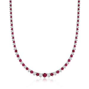 Op de afbeelding: Een delicate ketting met afwisselend ronde, levendige rode edelstenen en kleinere, heldere edelstenen. De ketting is gezet in een zilver- of witmetaal en wordt gepresenteerd tegen een witte achtergrond.