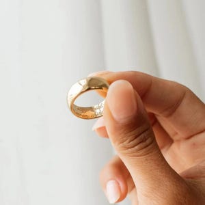 May include: A gold ring with the inscription "stay wild moon child" inside. The ring is held up against a white background.