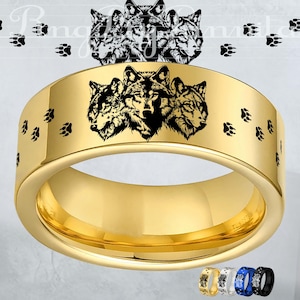 May include: A gold-coloured ring with a black wolf design. The ring has a wide band with three wolf faces and paw prints. Additional rings in gold, silver, white, blue, and black are shown at the bottom.