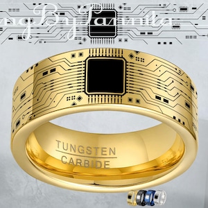 May include: A gold-colored tungsten carbide ring with a circuit board design. The ring features a black square in the center and the words "Tungsten Carbide" engraved on the band. The ring has a polished finish and a modern aesthetic.