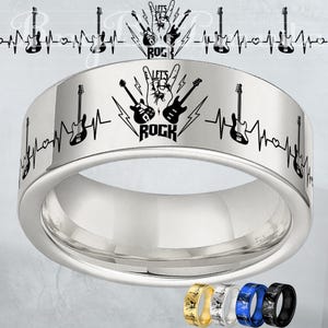 May include: A silver-colored ring with a black guitar and heartbeat design. The ring features the text "LET'S ROCK" and a series of guitars and heartbeats around the band. Additional rings in gold, silver, blue, and black are shown.