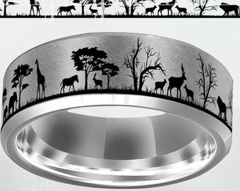 May include: A silver-colored ring with a brushed metal finish. The ring features a black silhouette design of an African savanna scene, including trees, giraffes, zebras, and deer. The ring has a polished inner band and a slightly rounded profile.