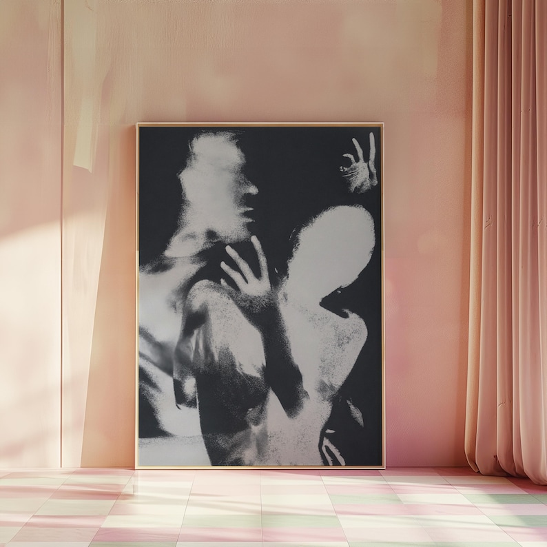 May include: Black and white art print in a gold frame. The artwork depicts two figures in an abstract style, with one figure partially obscured. The background is a soft pink, with a checkered floor and a curtain.