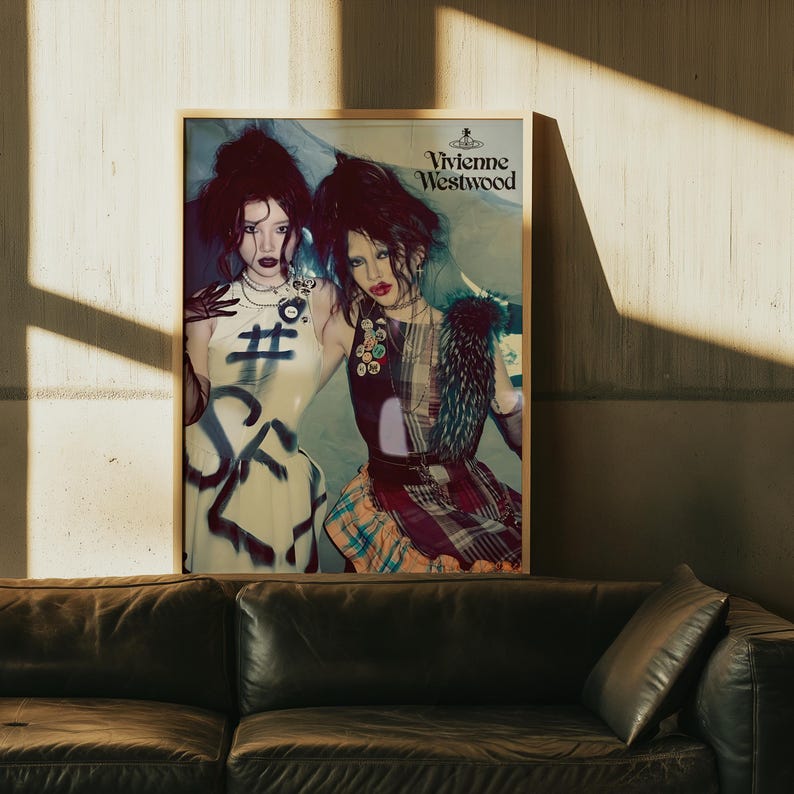 Peut inclure: Publicit&eacute; de mode encadr&eacute;e Vivienne Westwood avec deux mannequins. L'un porte une robe blanche avec du texte de style graffiti et un symbole di&egrave;se. L'autre porte une robe patchwork avec une jupe &agrave; carreaux et des accents de fourrure. Le logo est en haut &agrave; droite.