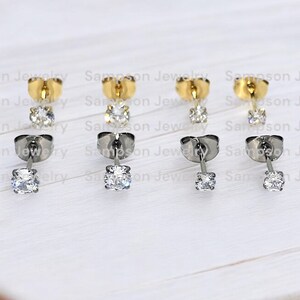 May include: Six pairs of earrings with a single clear stone on each earring. Three pairs have gold posts and three pairs have silver posts.