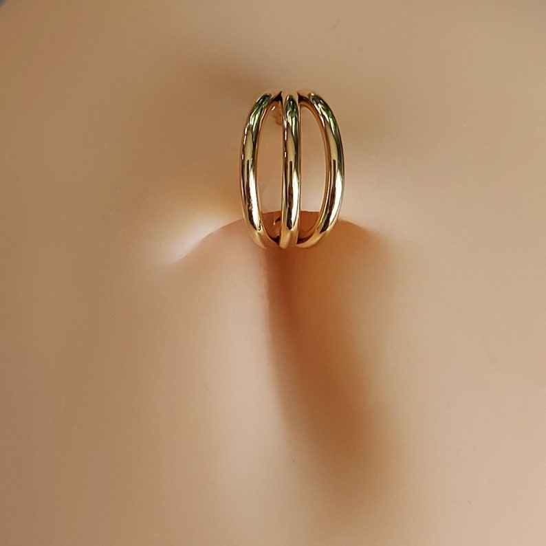 May include: Gold belly button ring with three interlocking circles.
