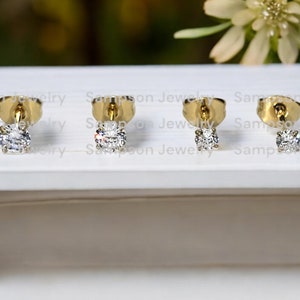 May include: Three pairs of gold stud earrings, each featuring a single round clear diamond.