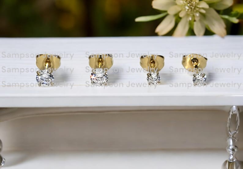 May include: Three pairs of gold stud earrings, each featuring a single round clear diamond.