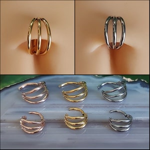 May include: Six nose rings in different colors. Three are gold, two are silver, and one is rose gold. Each ring has three bands.