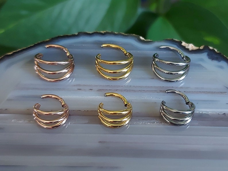 May include: Six nose rings with a triple hoop design. The rings are available in gold, silver, and rose gold.
