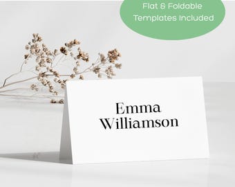 May include: A white folded card with the name "Emma Williamson" in black text. The card is on a white surface with a sprig of dried flowers and a green oval with the text "Flat & Foldable Templates Included". A Canva logo is in the bottom left corner.