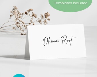May include: A white folded card with the name "Olivia Root" in elegant black script. The card is displayed on a white surface, with a sprig of dried flowers and a green oval with the text "Flat & Foldable Templates Included". A Canva logo is in the bottom left.