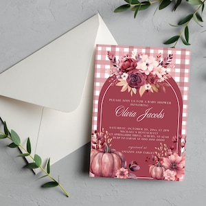 May include: A baby shower invitation featuring a floral arrangement with burgundy and pink flowers, pumpkins, and the name "Olivia Jacobs." The invitation has a pink and white gingham background and is accompanied by a white envelope.