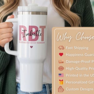 Pode incluir: Caneca t&eacute;rmica branca com al&ccedil;a, com o nome "Isabelle" e o texto "RBT REGISTERED BEHAVIOR TECHNICIAN" em rosa. Um pequeno cora&ccedil;&atilde;o rosa est&aacute; abaixo do nome. A caneca tem uma tampa branca e um canudo.