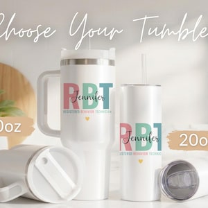 Pode incluir: Canecas brancas com texto personalizado, incluindo uma caneca de 1183 ml com al&ccedil;a e uma caneca de 591 ml. As canecas apresentam o texto "RBT Jennifer Registered Behavior Technician" em rosa, azul-petr&oacute;leo e preto, com um pequeno cora&ccedil;&atilde;o amarelo.