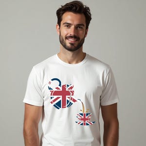 May include: White t-shirt with a graphic of a teapot pouring tea into a teacup, both decorated with the Union Jack. The teapot has a blue handle and spout. The tea is brown. The design is centered on the shirt, a patriotic theme.
