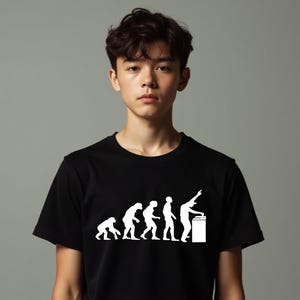 Może przedstawiać: Czarny t-shirt z białą grafiką przedstawiającą ewolucję człowieka, zakończoną DJ-em przy gramofonie. Projekt pokazuje etapy rozwoju człowieka, a ostatnia postać obsługuje sprzęt DJ-ski. Koszulka jest noszona przez osobę.