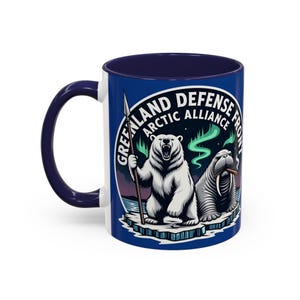 Puede incluir: Una taza de cerámica blanca con interior y asa azul marino. La taza presenta un gráfico de un oso polar sosteniendo una lanza y una morsa con un cigarro, con el texto "GREENLAND DEFENSE ARCTIC ALLIANCE FRONT" en un diseño circular.