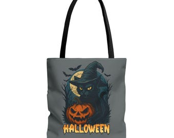 May include: A gray tote bag featuring a Halloween design. The graphic depicts a black cat wearing a witch hat, holding a carved pumpkin, with a full moon and bats in the background. The word "HALLOWEEN" is printed in orange.