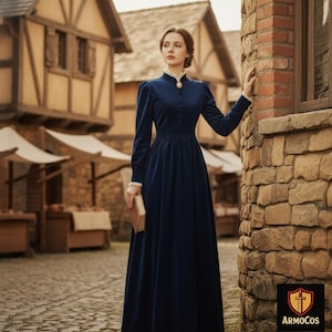 Puede incluir: Un vestido largo de terciopelo azul marino con mangas largas, cuello alto y botones. El vestido tiene detalles de encaje blanco en el cuello y los puños. La mujer sostiene un libro en un entorno histórico.