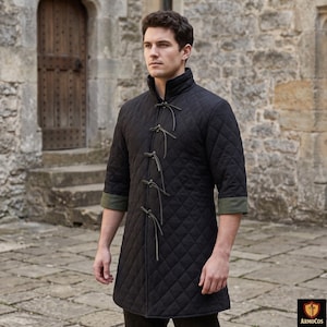 Può includere: Un cappotto nero trapuntato con collo alto e maniche a tre quarti. Il cappotto presenta un motivo a rombi ed è allacciato con lacci in pelle. Le maniche hanno un bordo verde. Fa parte di una collezione di abbigliamento medievale o storico.