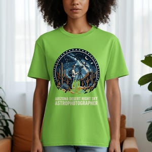 May include: A lime green t-shirt featuring a circular graphic of an Arizona desert night sky scene with a person using a telescope. The text "ARIZONA DESERT NIGHT SKY ASTROPHOTOGRAPHER" is printed below the graphic.