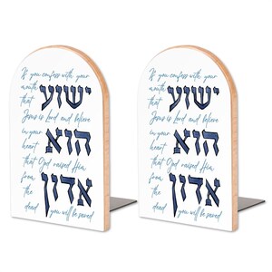 May include: A pair of arched wooden bookends with a white front surface featuring blue Hebrew calligraphy and the English text: If you confess with your mouth that Jesus is Lord and believe in your heart that God raised Him from the dead you will be saved.