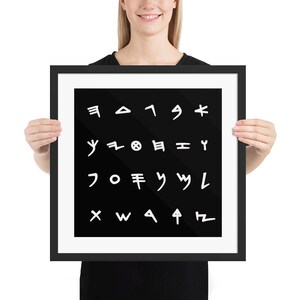 May include: A square framed wall art piece featuring a black background with twenty white, hand-drawn style symbols arranged in four rows of five. The artwork is enclosed in a simple black frame with a white mat border, presenting a clean, high-contrast design.