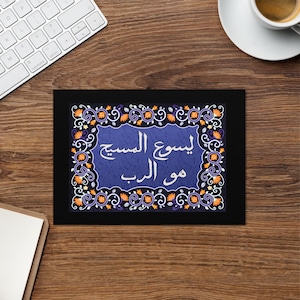 Könnte beinhalten: Gerahmter Druck mit arabischem Text auf blauem Hintergrund, umgeben von einem dekorativen Rand aus orangefarbenen, lila und weißen Blumenmustern. Der Druck liegt auf einer dunklen Holzoberfläche, mit Tastatur und Kaffeetasse.